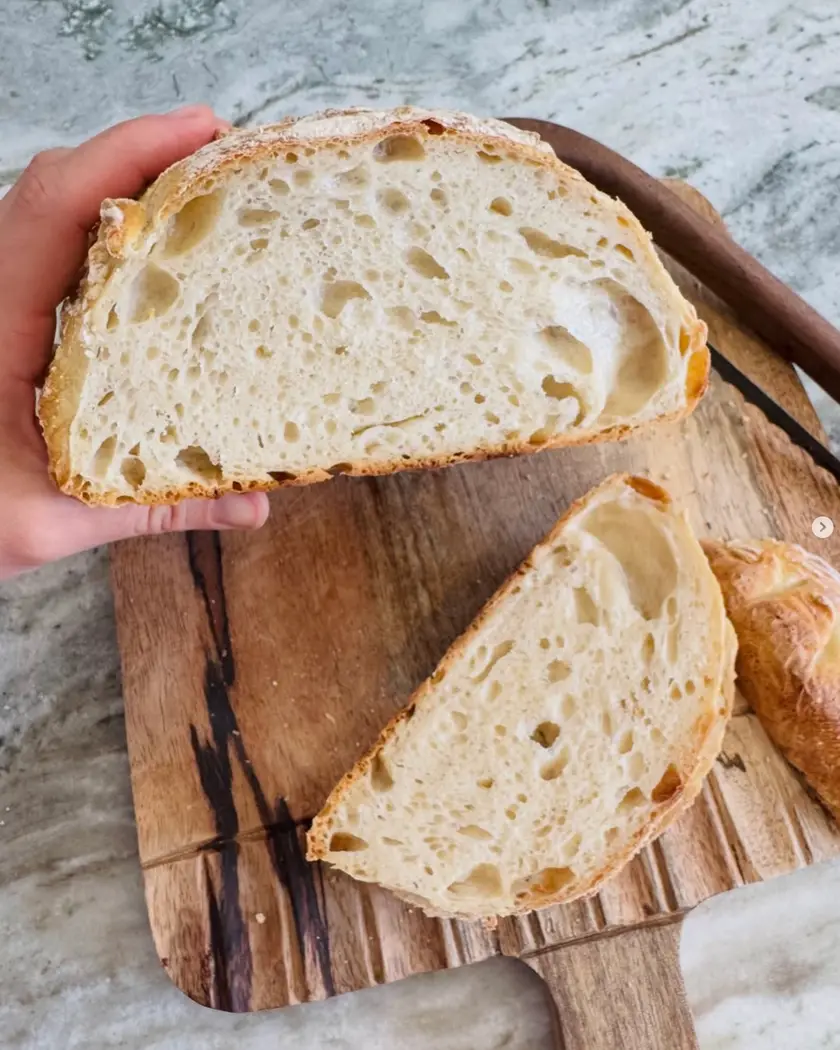 A sourdough loaf cut in half, showing an open, airy crumb