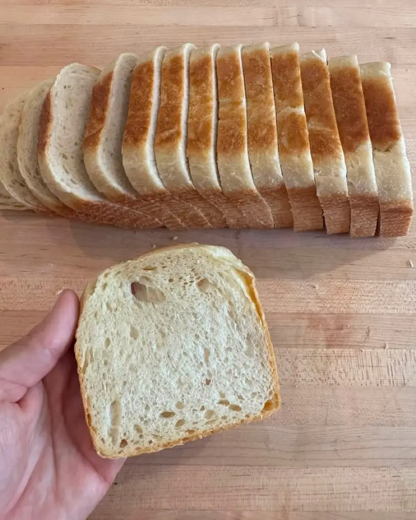 A sliced sandwich loaf on a wooden board